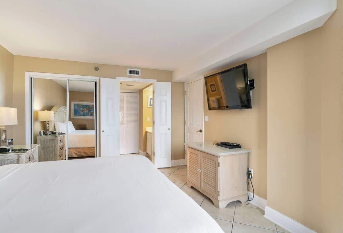 A hotel room with a large bed, a TV mounted on the wall, a bedside table, and a wardrobe.