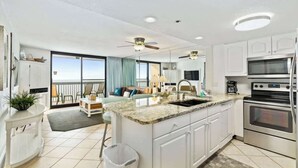 A modern kitchen with white cabinetry, a granite countertop, and stainless steel appliances. - SunDestin Resort Unit 1406 (Destin)