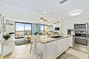 A modern kitchen with white cabinetry, a granite countertop, and stainless steel appliances. - SunDestin Resort Unit 1406 (Destin)