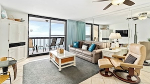 A spacious living room with a balcony, a sofa, a coffee table, and a chair. - SunDestin Resort Unit 1406 (Destin)