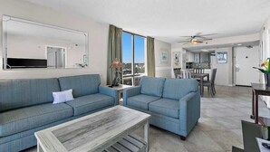 Ein modernes Wohnzimmer mit zwei Sofas, einem Couchtisch und Blick auf die Stadt.