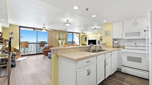Una cocina moderna con armarios blancos, una isla grande y vistas al exterior.