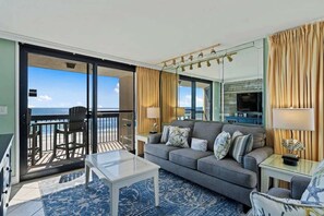 A living room with a sofa, coffee table, and a view of the ocean through large sliding glass doors. - SunDestin 2BR Condo Sleeps 7 With Expansive Gulf Views (Destin)