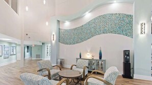 A spacious lobby with a curved wall mosaic, a round table with chairs, and a cash machine. - SunDestin 1BR Condo With Spacious Layout and Sleeps 6 - Unit 0314 (Destin)