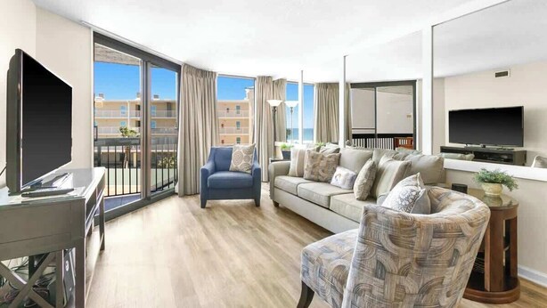A modern living room with a sofa, armchair, and a TV. - SunDestin 1BR Condo With Spacious Layout and Sleeps 6 - Unit 0314 (Destin)