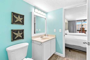 A hotel bathroom with a white toilet, a sink with a mirror, and two star decorations on the wall. - SunDestin 1BR Condo With Spacious Layout and Sleeps 6 - Unit 0314 (Destin)