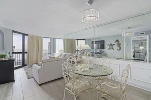 Relax in a stylish living room with a glass dining table, comfortable sofa, and city view.