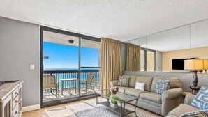 A modern living room with a balcony, a sofa set, a coffee table, and a TV.
