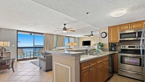 A modern kitchen with a central island, stainless steel appliances, and a view to the outside.