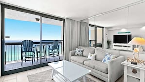 En moderne stue med balkon, sofa, sofabord og fjernsyn.