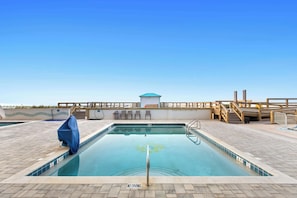 A swimming pool with a 'NO DIVING' sign, a covered bench, and a wooden deck with a railing.