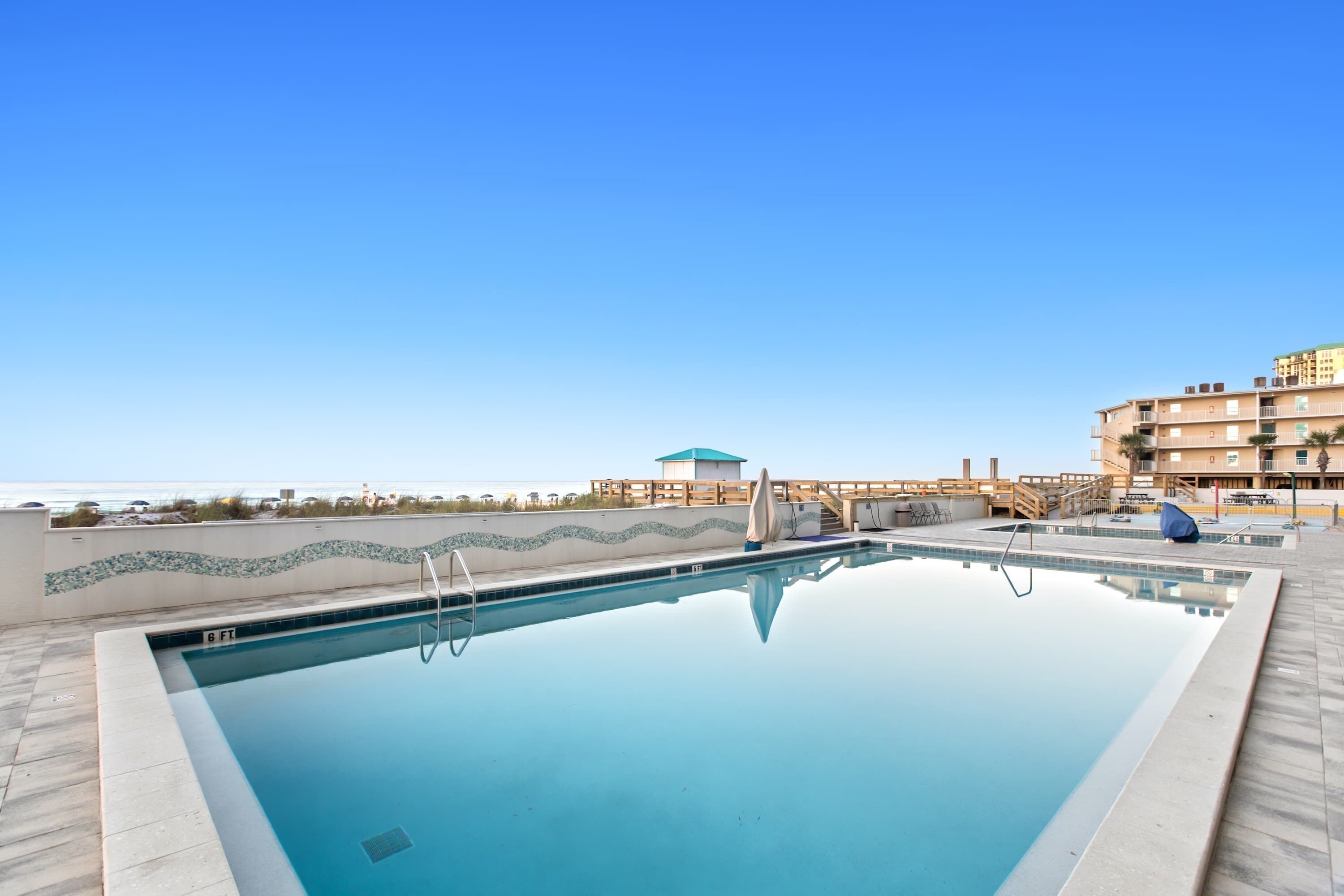 Une piscine rectangulaire à l’eau d’un bleu limpide, entourée d’une terrasse carrelée.
