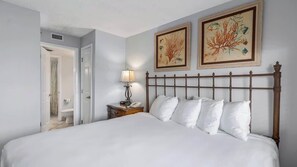 A neatly made bed with white linens, a wooden headboard, and two framed botanical prints on the wall. - SunDestin Beach Retreat With Bright Open Living and Gulf Scenery (Destin)