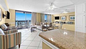 A spacious living area with a balcony, a kitchen, and a dining area. - Beachfront 1BR With Family Layout and Gulf Views -SunDestin Resort Unit 0406 (Destin)