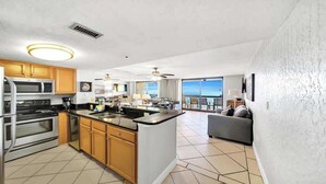 Una cocina moderna con una isla central, un comedor con vistas y una sala de estar con balcón.