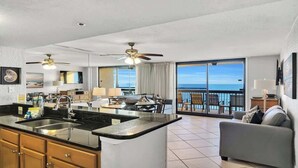 Una habitación de hotel moderna con cocina, una mesa de comedor y un balcón con vista al océano.