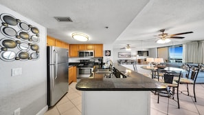 Enjoy meals in this kitchen with a central island, sink, and bar stools, offering a view of the ocean through large windows.