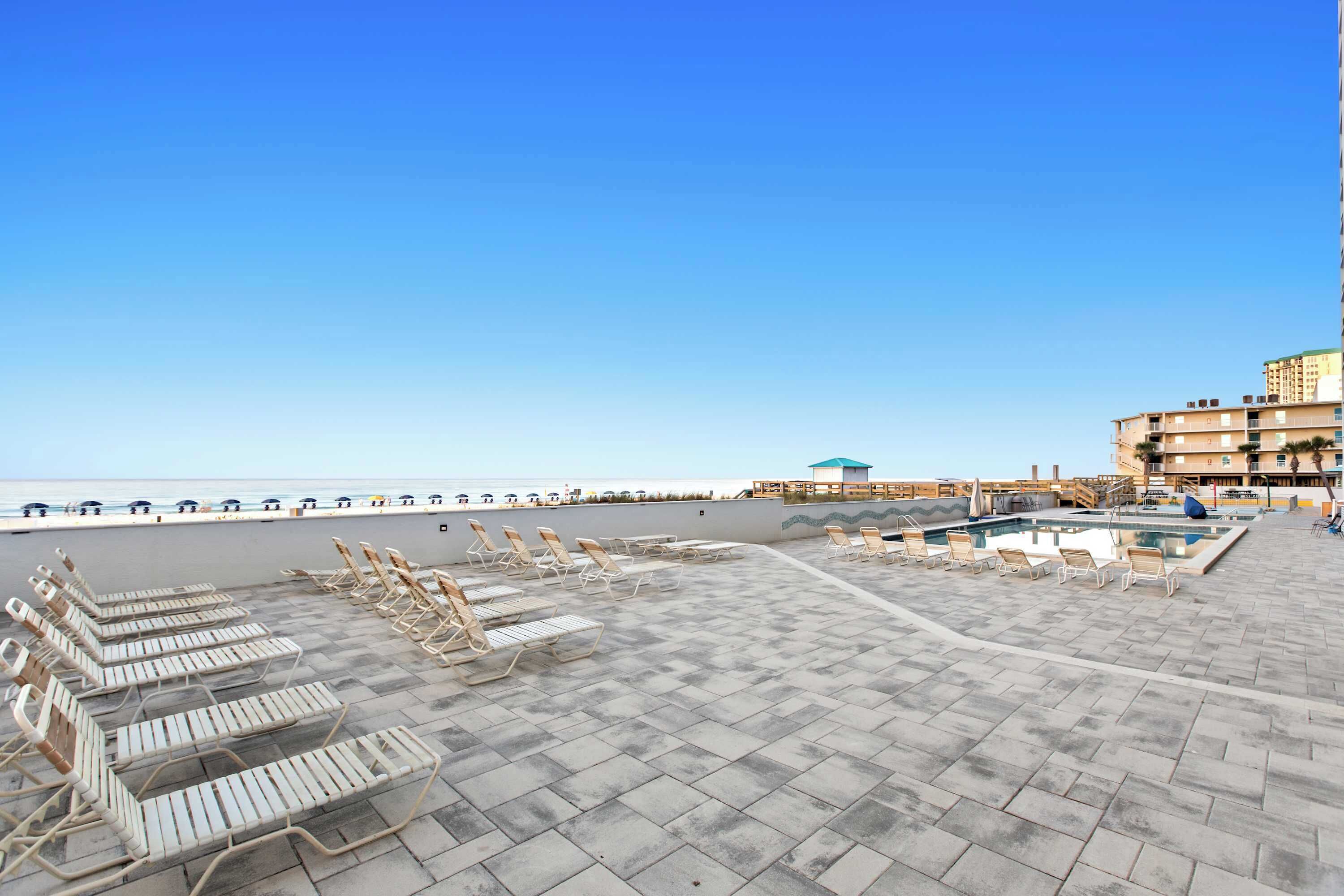 A rooftop pool area with lounge chairs and a view of the sea.