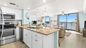 A modern kitchen with white cabinets, a granite countertop, and stainless steel appliances. - SunDestin Resort Unit 1505 (Destin)