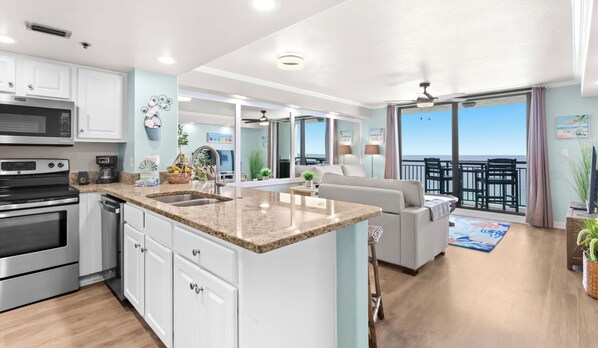 A modern kitchen with a central island, a dining area with a view, and a balcony with a view. - SunDestin Resort Unit 1505 (Destin)