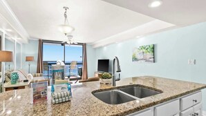A modern kitchen with granite countertops, a double sink, and a ceiling fan. - SunDestin Resort Unit 1505 (Destin)