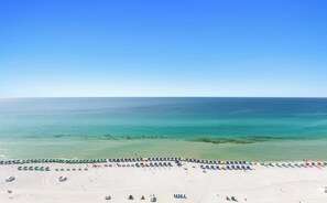 A beach with rows of umbrellas and a clear view of the ocean.