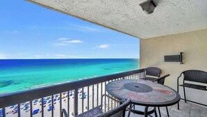 A balcony with a view of the ocean, a round table, and two chairs. - SunDestin Resort Unit 1509 (Destin)