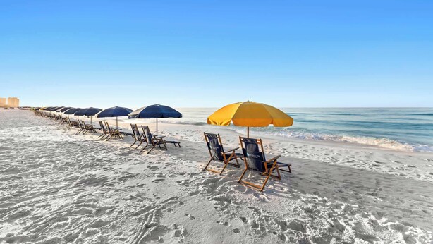 A beach with rows of beach chairs and umbrellas, a clear sky, and the ocean in the background. - SunDestin Resort Unit 1509 (Destin)