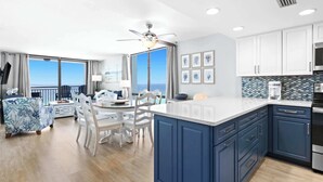 A modern kitchen with a large island, white cabinets, and a view of the ocean. - SunDestin Resort Unit 1112 (Destin)