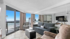 Ein modernes Hotelzimmer mit Balkon, einer Couch, einem Couchtisch und einem Fernseher.