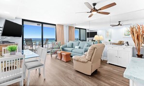 A modern living room with a balcony, a dining area, and a kitchen.