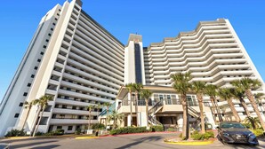A multi-story hotel with a modern design, featuring balconies, a central tower, and palm trees in the foreground. - 1BR Condo Sleeps 6 With Gulf Views and In-Unit Laundry - SunDestin Unit 0308 (Destin)