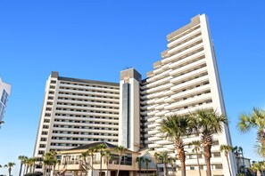 Un hôtel à plusieurs étages, doté d’une architecture moderne, comprenant des balcons et un atrium central.