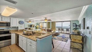 A spacious kitchen with a central island, a dining area with a view, and a balcony with a view. - Renovated SunDestin 1BR Condo With Panoramic Gulf Views (Destin)