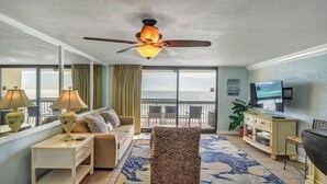 A hotel room with a balcony, a sofa, a television, and a ceiling fan. - Renovated SunDestin 1BR Condo With Panoramic Gulf Views (Destin)
