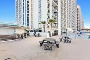 A rooftop patio with outdoor seating and a view of a high-rise building. - SunDestin Resort Unit 0212 (Destin)