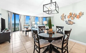 A modern living room with a dining area, large windows, and a view of the ocean. - 1BR Beachfront Living with Unforgettable Gulf Scenery (Destin)