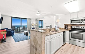 A modern hotel room with a kitchen, a balcony with a view, and a living area with a sofa and a coffee table. - SunDestin Resort Unit 0204 (Destin)