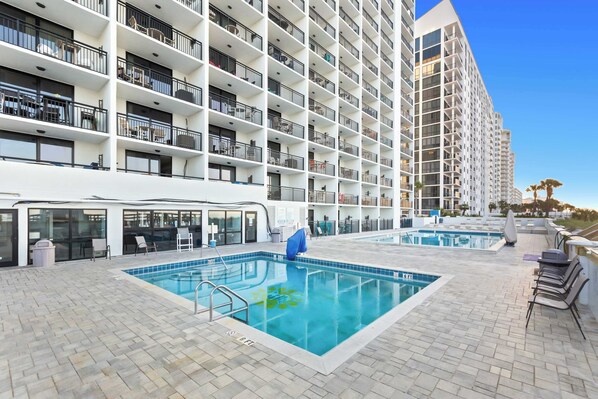 A hotel with a rooftop pool, multiple balconies, and a modern architectural design.