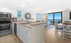 A modern kitchen with built-in appliances, a dining area with a view, and a balcony with outdoor seating.