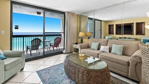 A hotel room with a balcony, a sofa, a coffee table, and a TV. - SunDestin Resort Unit 0904 (Destin)