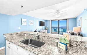 A kitchen with granite countertops, a sink, and a dining area with a view.