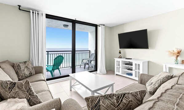 A modern living room with a balcony, a flat-screen TV, and a white entertainment unit.
