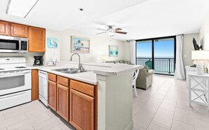 A modern kitchen with a central island, a dining area with a view, and a balcony with a view.