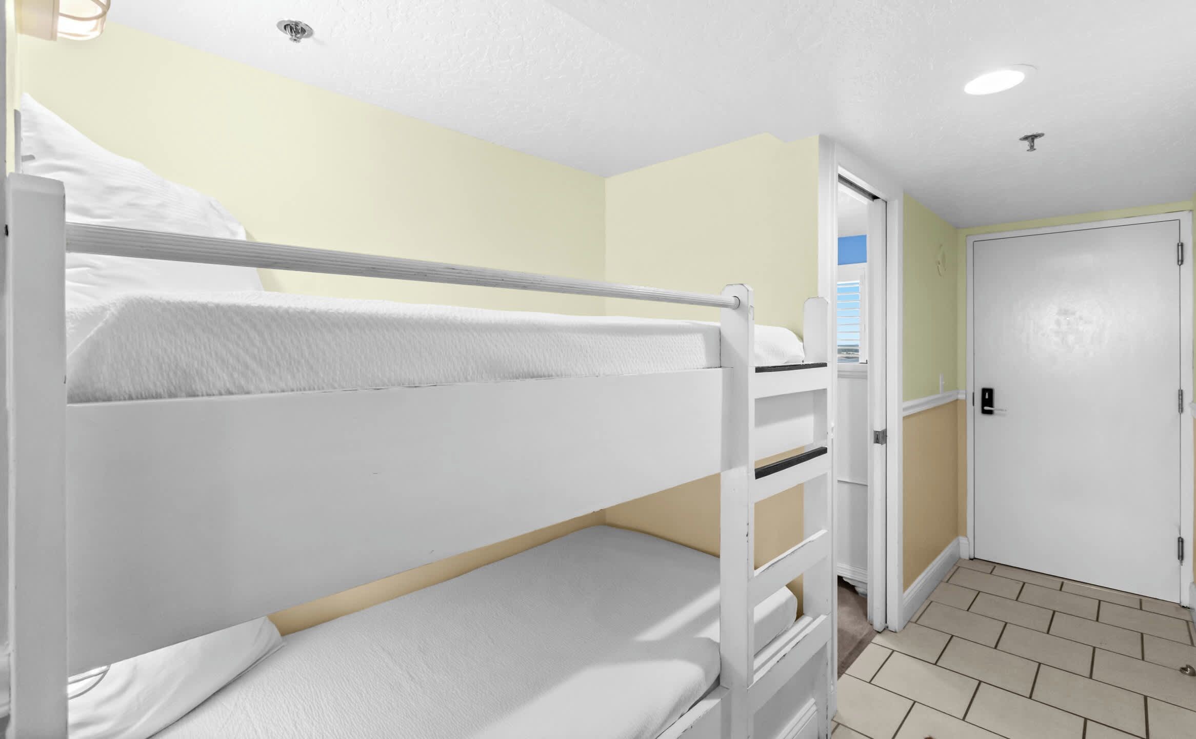 Une chambre avec un lit superposé, une porte et une fenêtre.