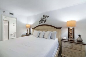 A neatly made bed with white linens, a wooden headboard, and two bedside lamps. - SunDestin Resort Unit 0708 (Destin)