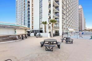 A rooftop patio with outdoor seating and a view of a high-rise building. - SunDestin Resort Unit 0708 (Destin)