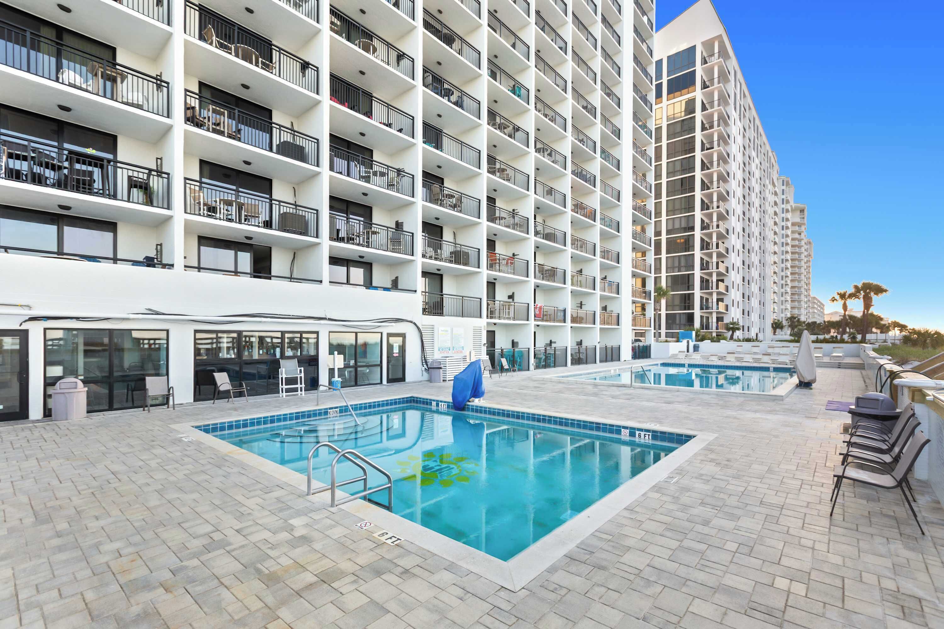 A hotel with a rooftop pool, multiple balconies, and a modern architectural design.