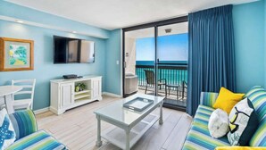Ein Zimmer mit Balkon, Fernseher, Sofa und Essecke.