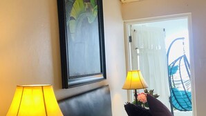 Une chambre d’hôtel avec un lit, deux lampes, un tableau encadré, un climatiseur et une vue sur l’extérieur.